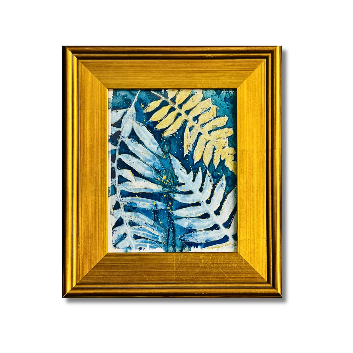 A framed botanical art print featuring textured blue and yellow fern leaves, enclosed in a wide gold frame against a white background.