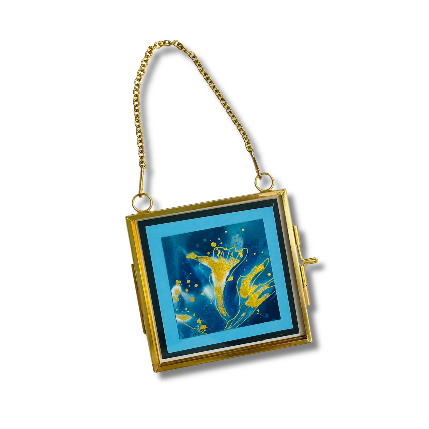 A square gold-framed wall hanging or ornament with a hanging chain, featuring a blue and gold abstract artwork on the front.