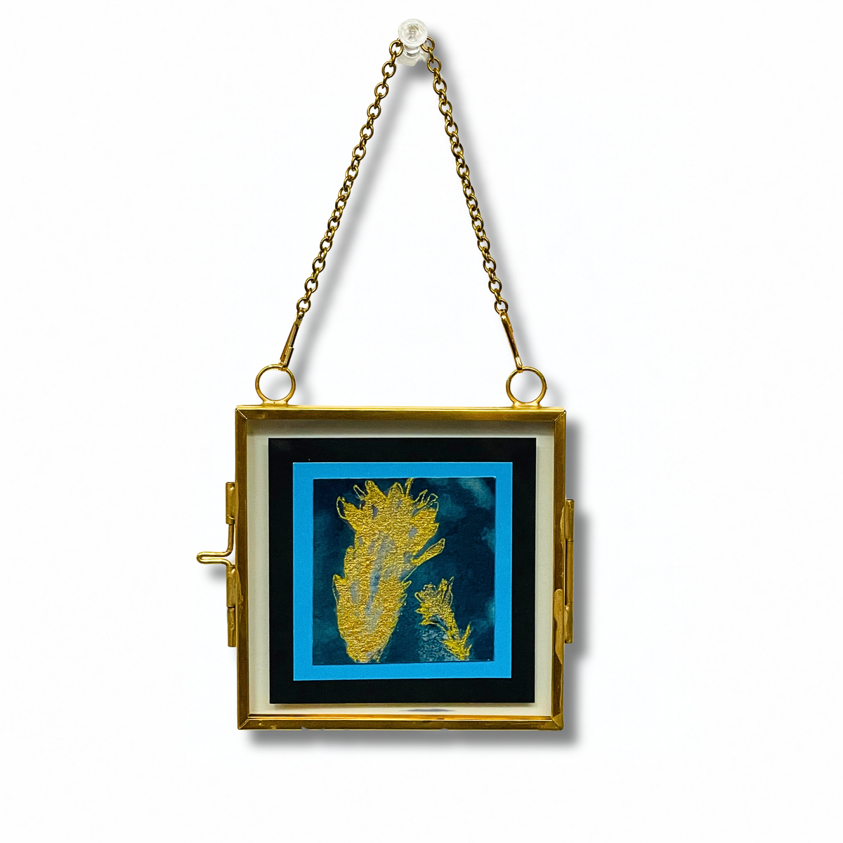 A gold-framed hanging wall mirror with a decorative inset artwork featuring gold french lavender on a blue background, suspended by a gold chain against a white wall.