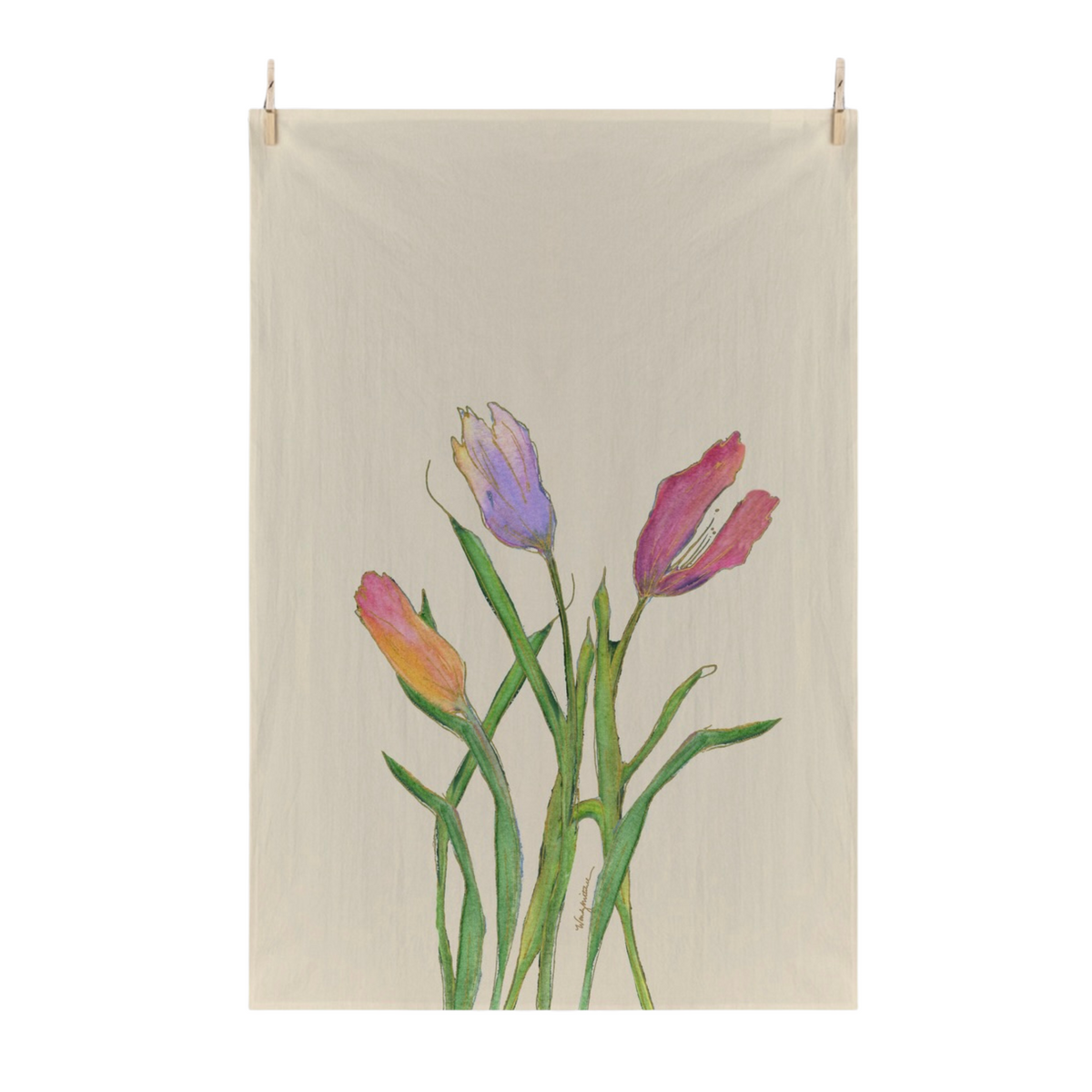 A cream colored flour sack tea towel with a painted floral design of tulips in pink, purple, and orange with green stems, suspended by two small wooden clips against a white background.