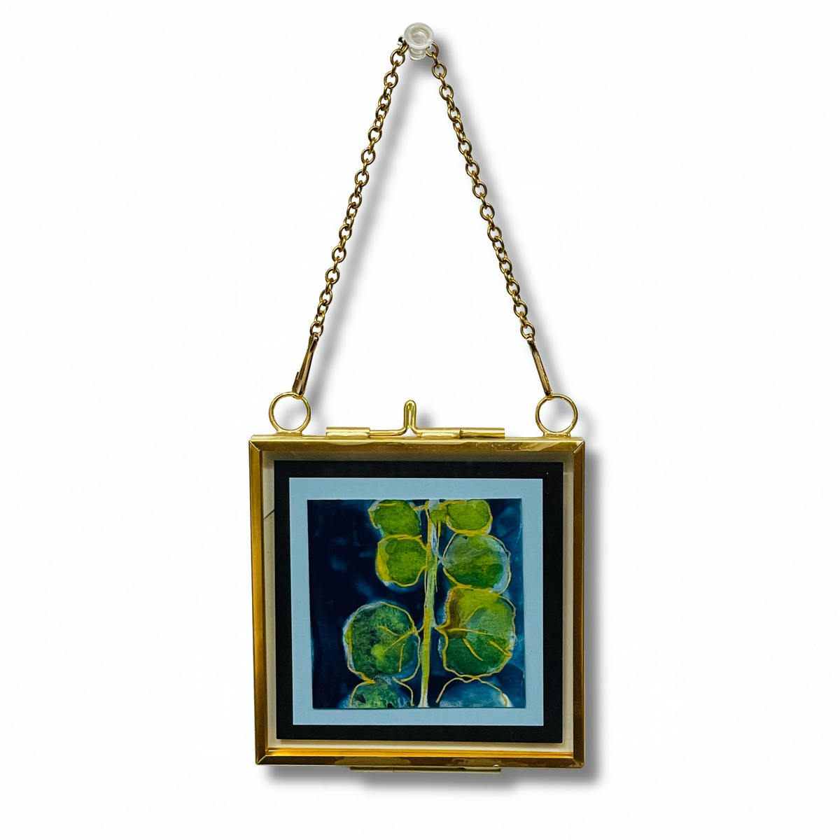 A square gold-tone clutch bag with a hinged clasp and hanging chain, featuring a printed botanical design of green leaves on a dark blue background.