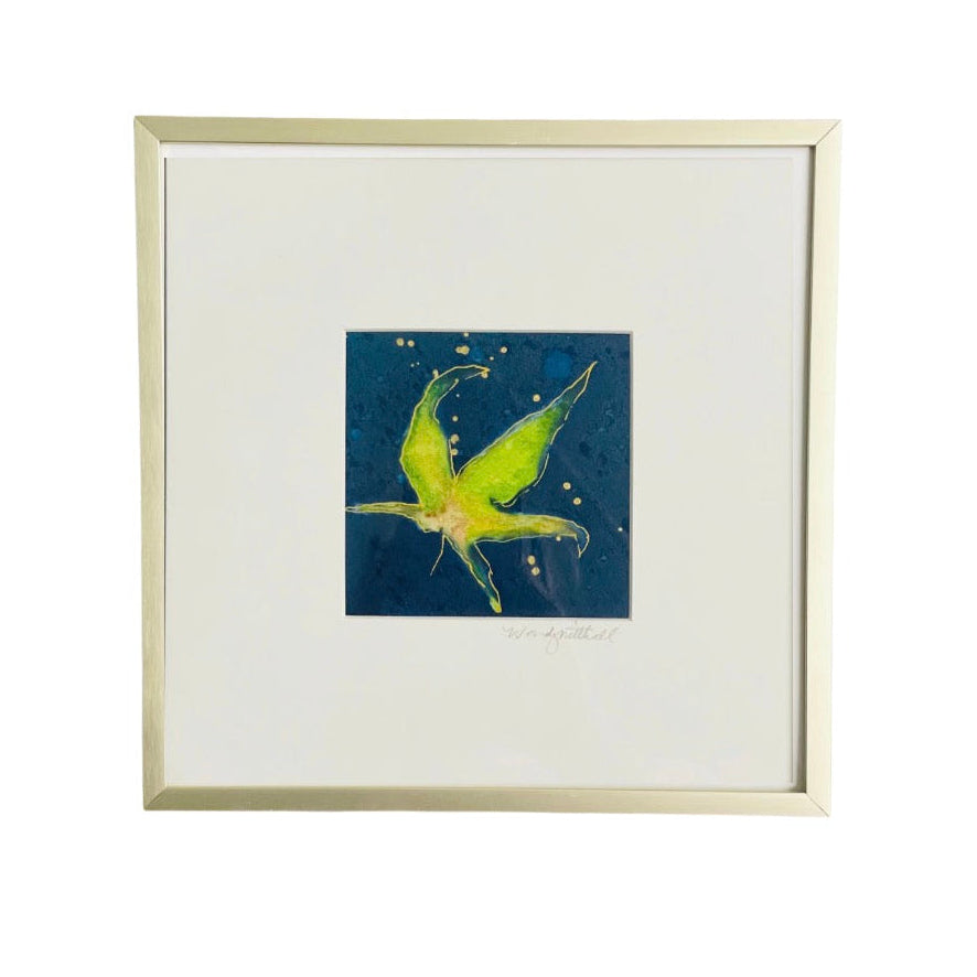 A framed art print featuring a vibrant green dragonfly on a textured dark blue background, presented in a light wood frame with a white mat.