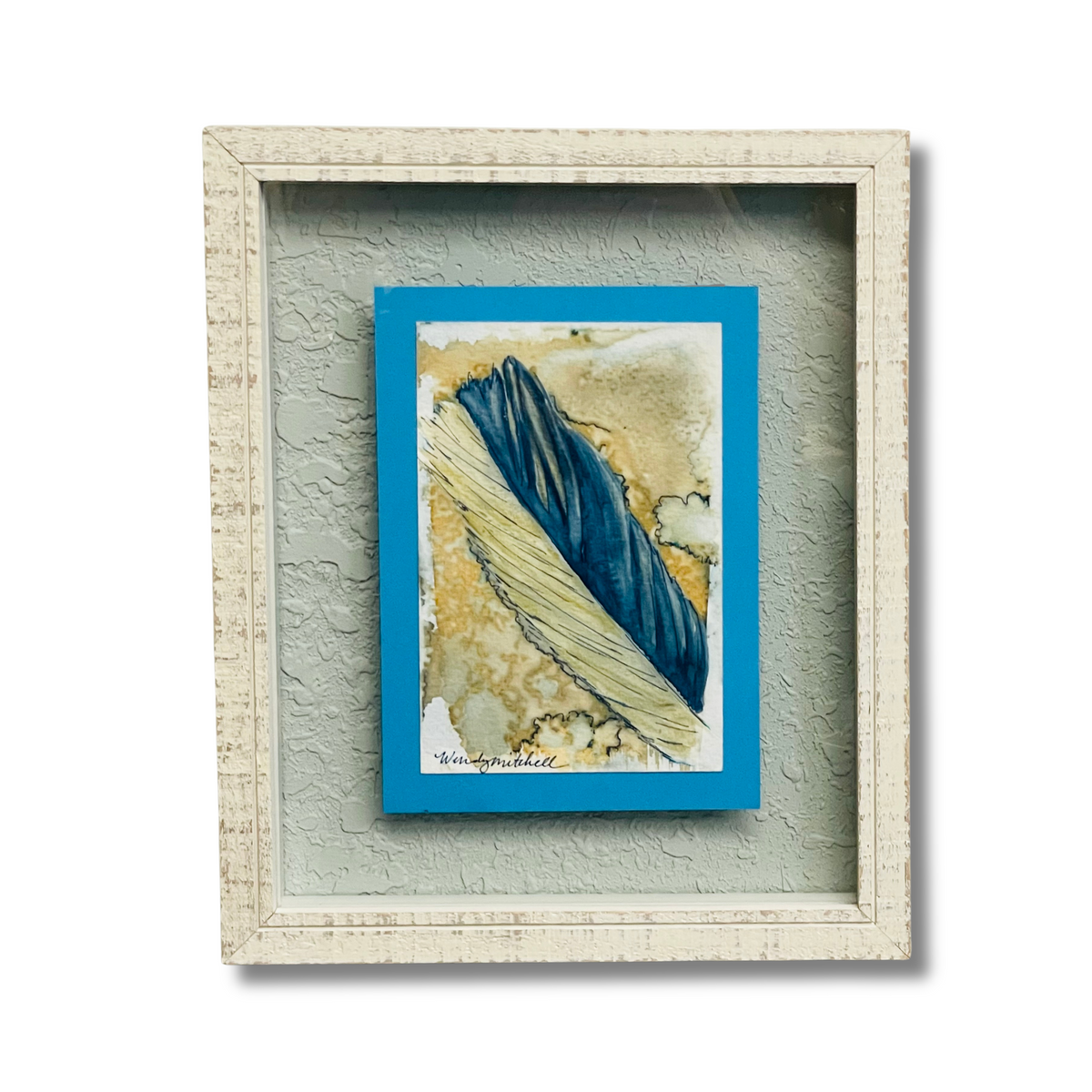Framed abstract art print featuring a textured feather design in deep blue and beige tones, set within a distressed off-white wooden frame against a light gray background.
