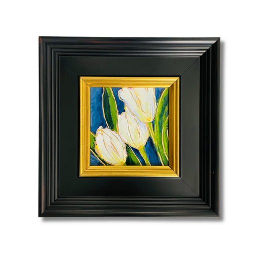 A framed painting of three white tulips with green leaves on a blue background, set in a black frame with a gold inner border, shown against a plain white background.