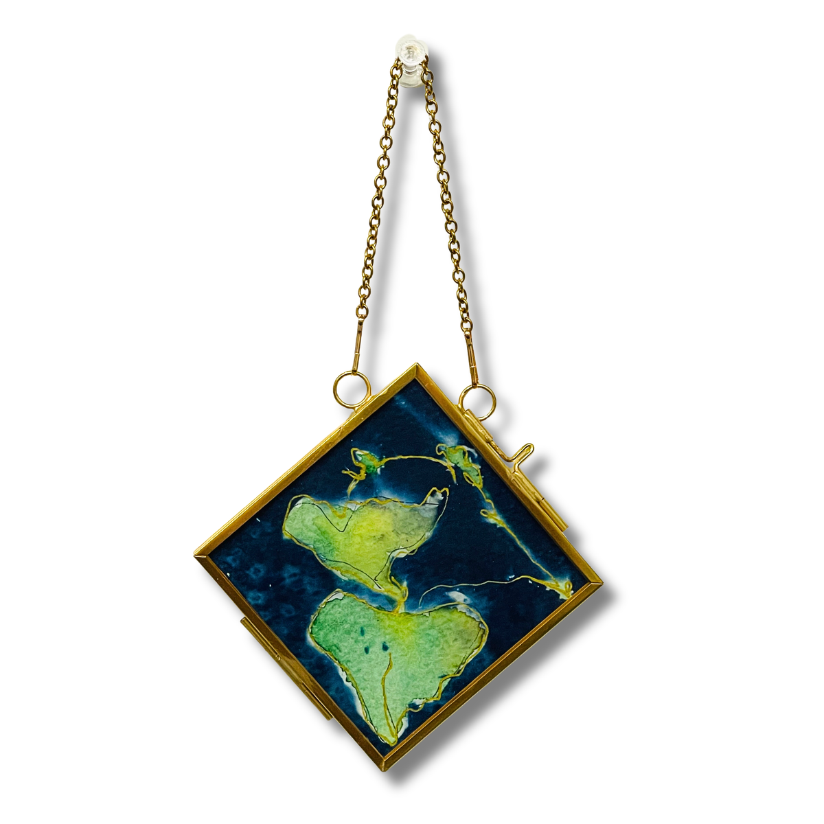 A square pendant with a gold-tone frame and chain, featuring an artistic depiction of green islands on a dark blue background, shown against a plain white background.