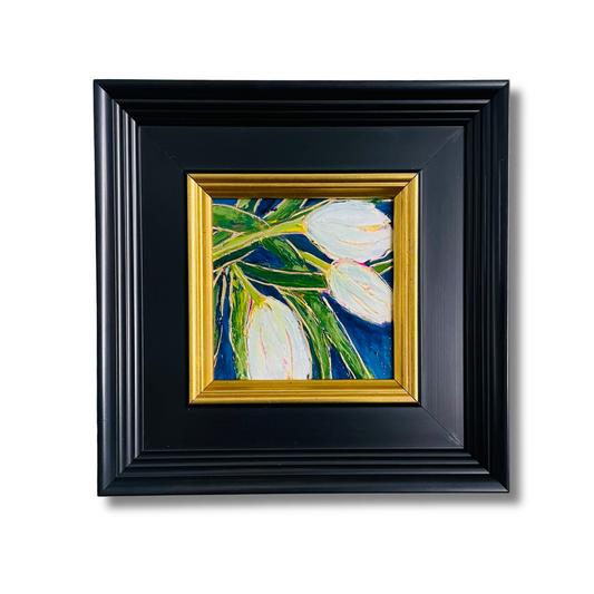 A framed painting of white tulips with green stems on a blue background, set in a black frame with a gold inner border, shown against a plain white background.